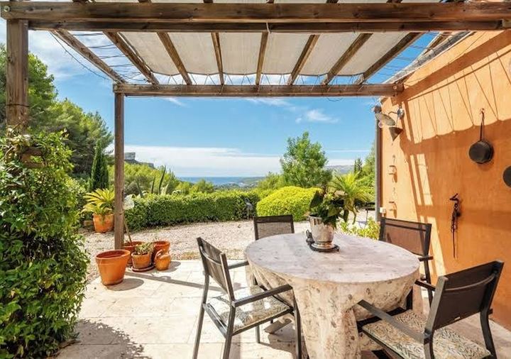 Terrasse sous pergola avec table de repas, face au jardin et à la mer